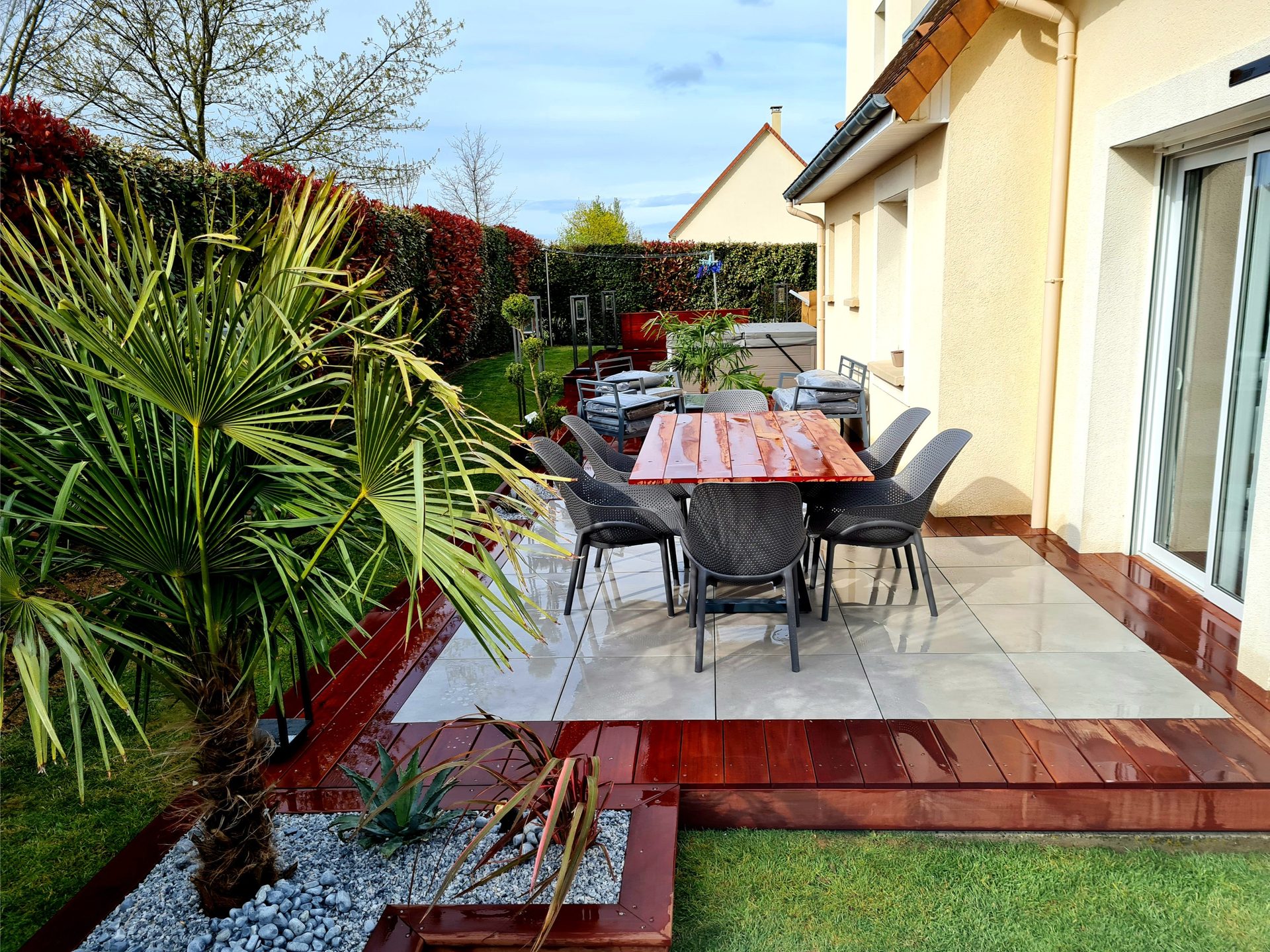 Terrasse carrelée bordée de lames en bois et de plantations