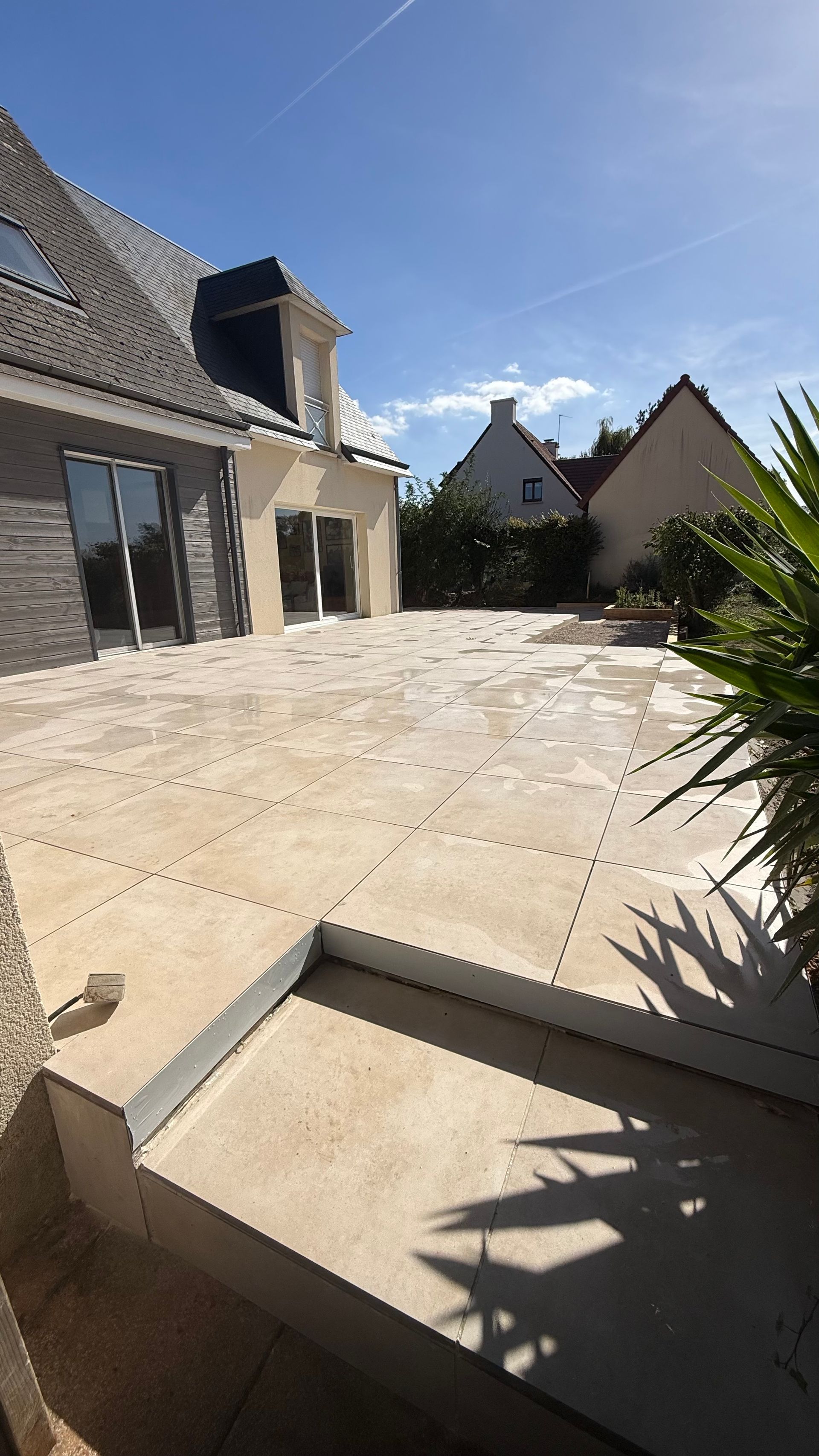 Grande terrasse en dalles avec marches devant une maison