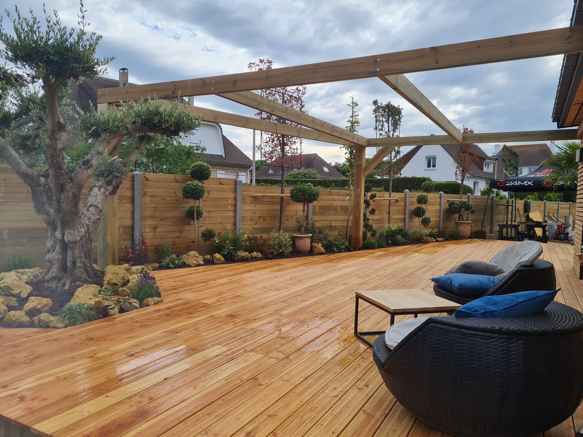 Terrasse en bois avec structure de pergola et massifs plantés