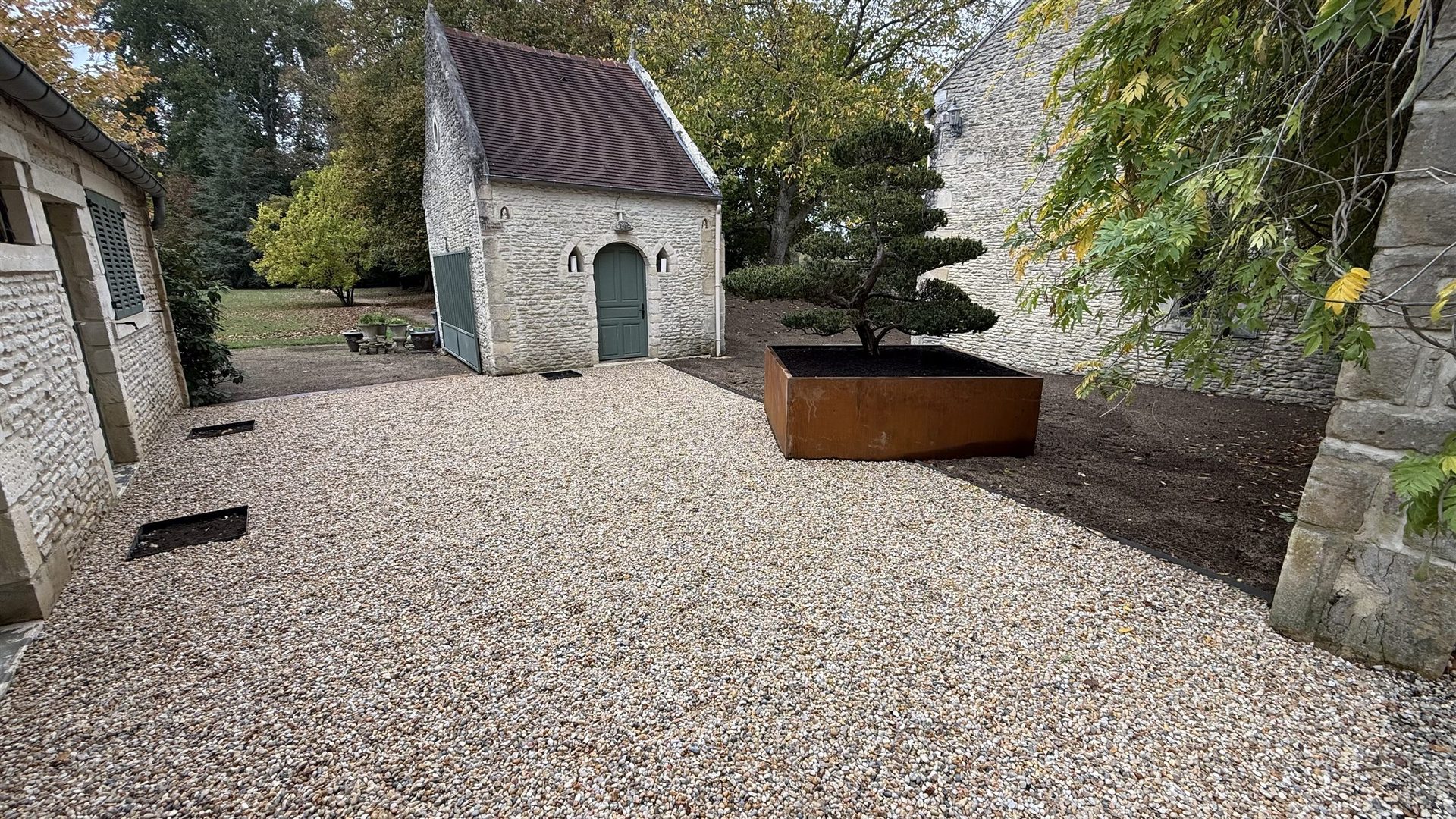 Cour gravillonnée entre bâtiments en pierre