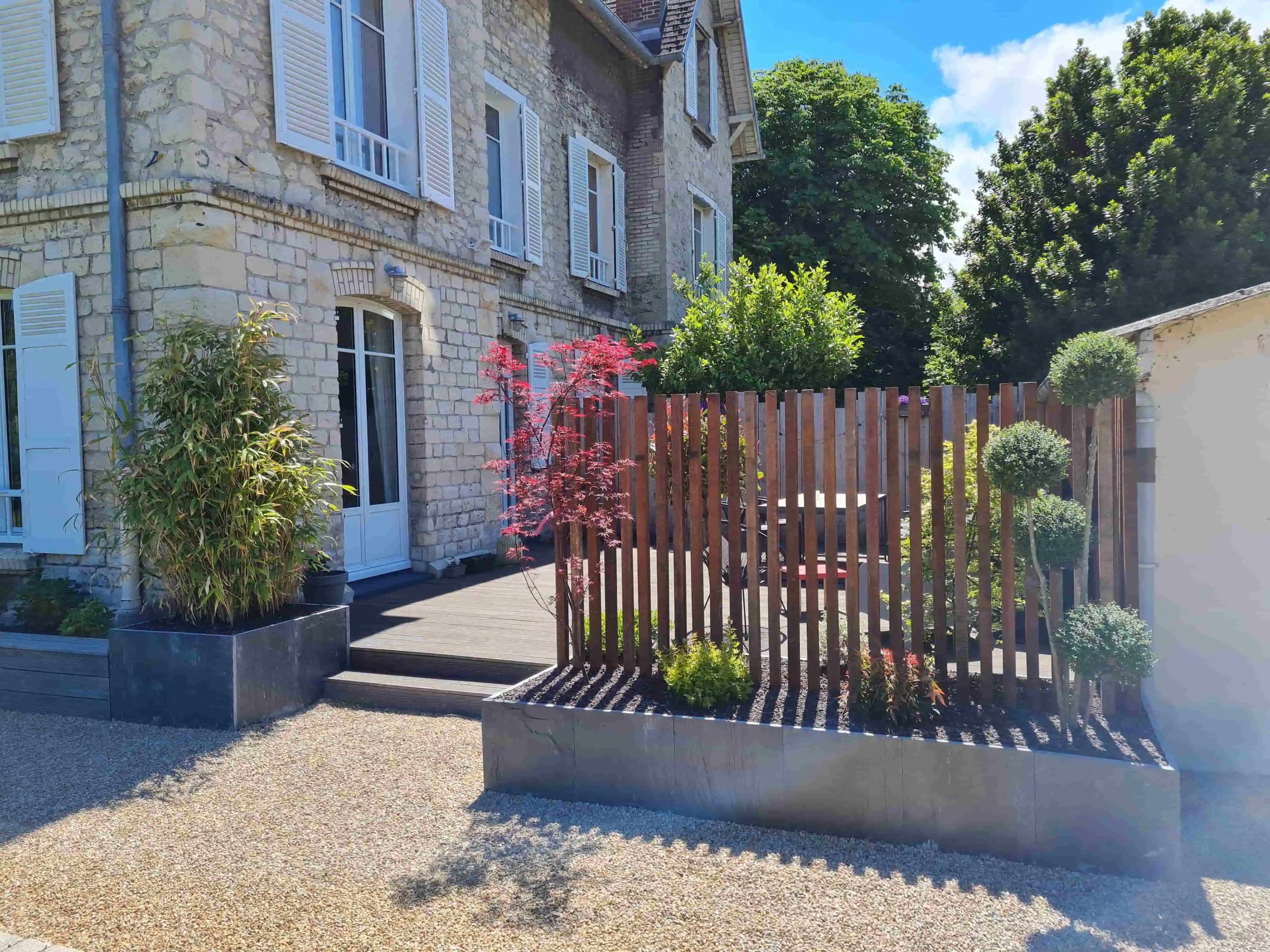Clôture moderne et maison en pierre.
